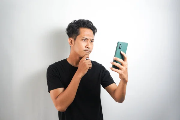 Eftertänksam Asiatisk Man Som Står Och Håller Mobil Isolerad Vitt — Stockfoto