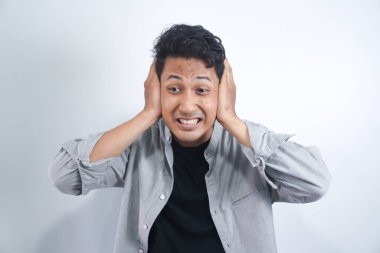 İki kulağını da beyaz arka planda tutan genç bir adamın portresi. Yüksek sesten acı çekiyor..