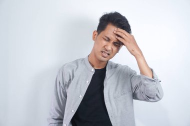 Asyalı genç adam sıkı çalışma gününden sonra baş ağrısı çekiyor.