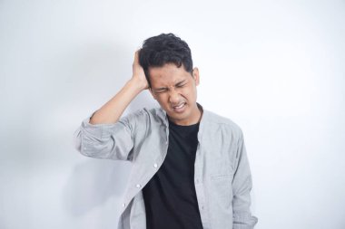 Asyalı genç adam sıkı çalışma gününden sonra baş ağrısı çekiyor.