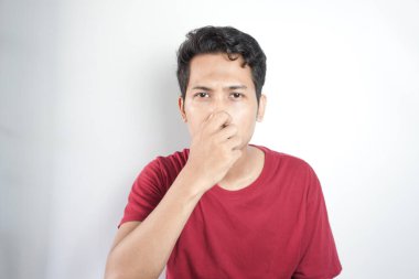 Portrait Of young Adult Man With Hand Covering Nose While Standing Against White Background