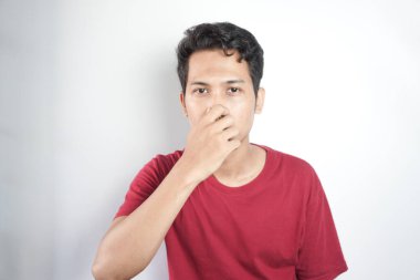 Portrait Of young Adult Man With Hand Covering Nose While Standing Against White Background