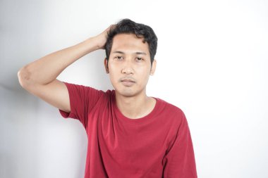 Young handsome man wearing casual t-shirt standing over white background confuse and wonder about question. Uncertain with doubt, thinking with hand on head. Pensive concept.