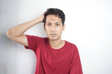 Young handsome man wearing casual t-shirt standing over white background confuse and wonder about question. Uncertain with doubt, thinking with hand on head. Pensive concept.