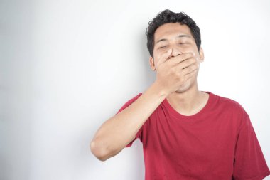 A tired man wearing a red top is yawning