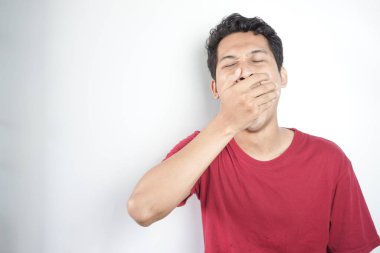 A tired man wearing a red top is yawning
