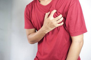 Göğsünde bir kalp ağrısı olan genç bir adam, sağ elinde..
