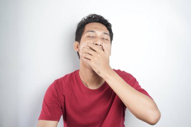 A tired man wearing a red top is yawning