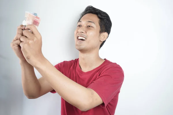 Cheerful man in plaid shirt holding rupiah bills over white background