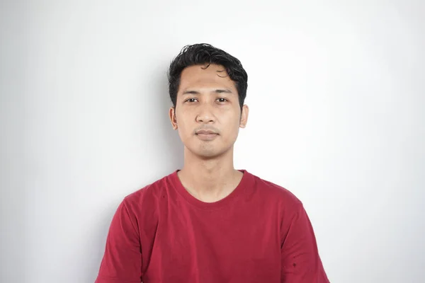 Young asian Indonesia man wearing t-shirt standing over isolated white background Relaxed with serious expression on face. Simple and natural looking at the camera.