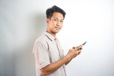 handsome asian young man with cell phone smiling and looking at camera