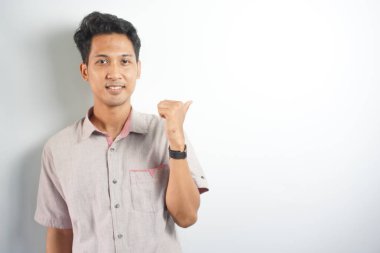 Tecrit edilmiş genç yakışıklı bir adam bir ürün sunmak için kenarı işaret ediyor.