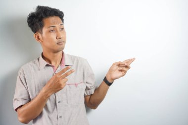 Tecrit edilmiş genç yakışıklı bir adam bir ürün sunmak için kenarı işaret ediyor.