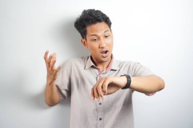 Happy and surprised Asian man who is looking at his watch. Shocked asian man in casual looking at watch