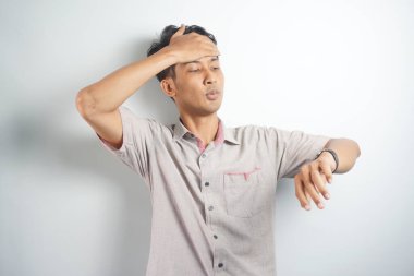 Shocked asian man in casual looking at watch