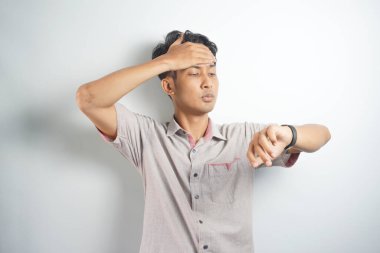 Shocked asian man in casual looking at watch