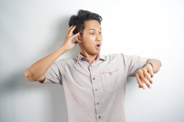 Shocked asian man in casual looking at watch