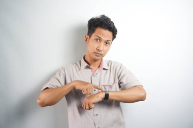 Handsome asian man wearing casual shirt In hurry pointing to watch time, impatience, upset and angry for deadline delay