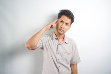 Handsome asian young man wearing shirt standing on white background confused and wondering about question. Uncertain with doubt, thinking. dream concept