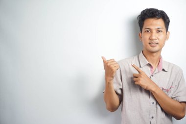 Tecrit edilmiş genç yakışıklı bir adam bir ürün sunmak için kenarı işaret ediyor.