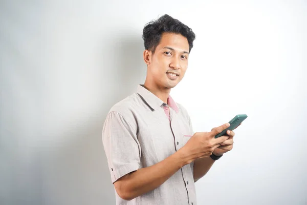 handsome asian young man with cell phone smiling and looking at camera
