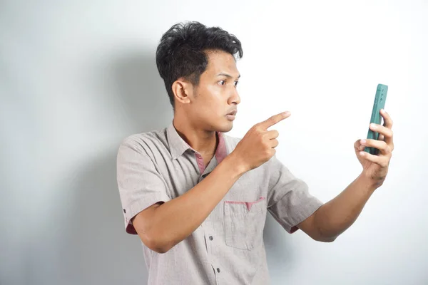 Young asian man angry, frustrated and furious with his phone, angry with customer service over white background.