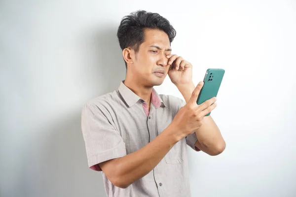 sad handsome asian man looking at notification on his cellphone