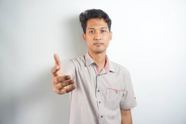 Kendine güvenen iş adamı el sıkışmak için elini uzatıyor, iş ortağını selamlıyor ve gülümsüyor, beyaz arka planda duruyor.