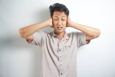 young handsome asian man covering both ears with hands isolated on white background