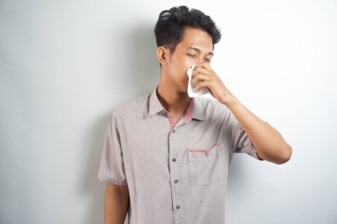 Forması giyen sağlıksız yakışıklı adamın yatay dikey çizgili ve gözlük, üfleme dokusuna burun. Erkek var grip, virüs ya da anti beyaz bir arka plana dayanır. Sağlıklı tıp ve insanlar kavramı