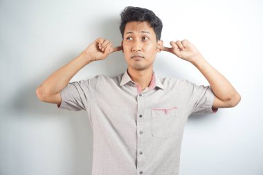 young handsome asian man covering both ears with hands isolated on white background
