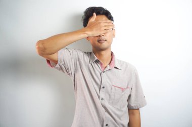 Young handsome Asian man wearing casual clothes smiling and laughing with hand on face covering eyes for surprise. blind concept.
