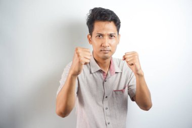 Hadi dövüşelim. Heyecanlı, kendinden emin erkek modelin portresi, yumruklarını kaldırması, boksör pozu vermesi, barda sarhoş olup da beyaz duvarın üzerinden birini yumruklamak istemesi.