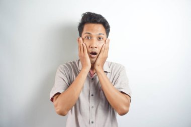 Young asian man wearing shirt surprised open mouth and hand holding cheek