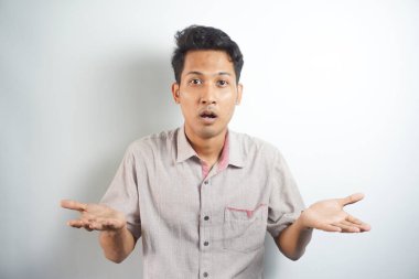 Handsome asian young man wearing shirt standing on white background confused and wondering about question. Uncertain with doubt, thinking. dream concept