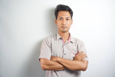 Handsome Asian young man with arms crossed over chest looking at camera
