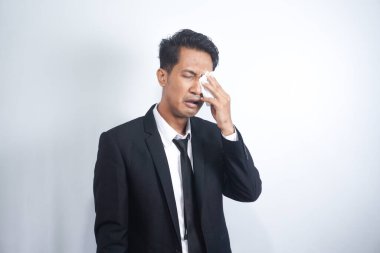 Business man wipe his eye. Asian young manager in dark black suit wipe eye with white tissue or napkin .