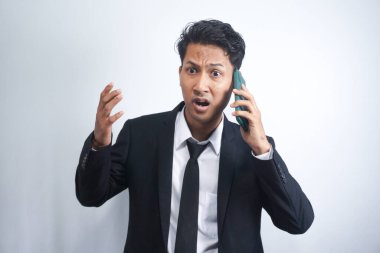 Genç Asyalı adamın telefonu aradığında kafası karışıyor ve şoka giriyor. Siyah gömlek giyen Endonezyalı adam..