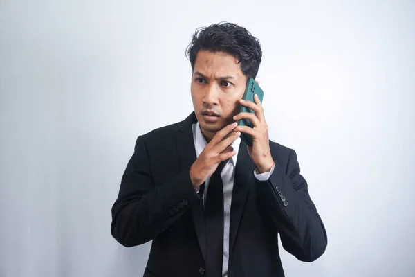Young Asian Man is confused and shocked when calling in the phone. Indonesian man wearing a black shirt.