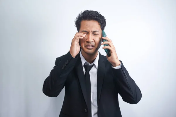 Young man crying over the bad news he is receiving on his phone. emotional man isolated on white background.