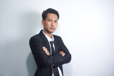 Confident successful corporate man in suit, cross arms on chest and smiling self-assured, standing against white background
