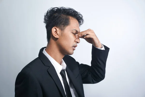 Asian young man stress tired and holding his nose suffer sinus pain fatigue from hard work.