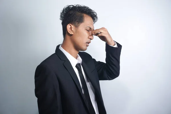 Asian young man stress tired and holding his nose suffer sinus pain fatigue from hard work.