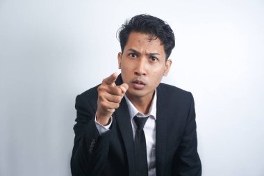 Sinirli genç adam kamerayı işaret ederek suçlu birini suçlar ya da beyaz arka planda izole edilmiş birini azarlar. Sinirli bir adam bağırıyor ve indeksi bozuluyor..