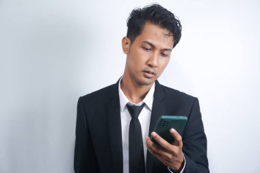 Photo of serious focused Asian man modern digital smart phone device, chats in social networks