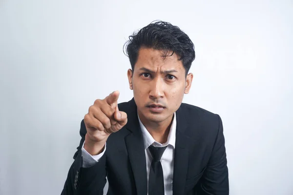Furious young man pointing forefinger to camera blaming someone as guilty, or scolding isolated on white background. Angry guy screaming and showing with index being annoyed.