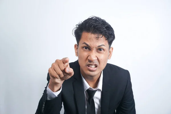 Furious young man pointing forefinger to camera blaming someone as guilty, or scolding isolated on white background. Angry guy screaming and showing with index being annoyed.