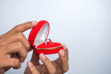 Man holding in his hands a red heart-shaped box with an engagement ring