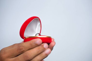 Man holding in his hands a red heart-shaped box with an engagement ring