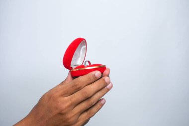 Man holding in his hands a red heart-shaped box with an engagement ring